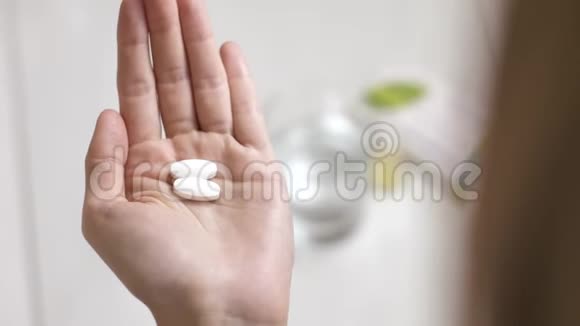 紧紧抓住女人手里拿着白色的药丸喝一杯水视频的预览图