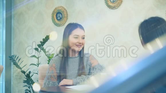 快乐美丽的女孩和她的女朋友坐在咖啡馆里在这期间讲个故事一起享受时光视频的预览图