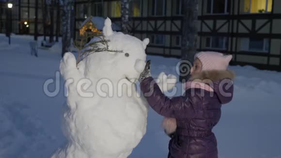 在雪地公园里堆雪人的小女孩视频的预览图