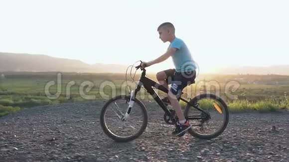 一个美丽的小男孩他在夏天在东方或阳光下在山区骑黑色自行车孩子视频的预览图
