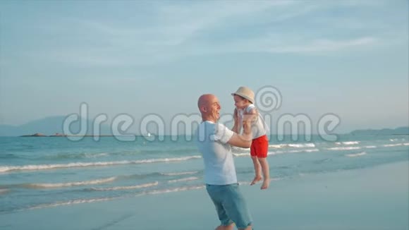 幸福的父子在日落时在海滩上玩和玩动作缓慢幸福家庭童年视频的预览图