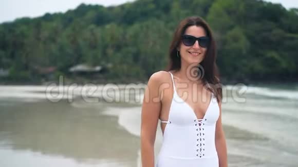 美丽的女人穿着白色泳衣在海滩上散步旅行和度假概念视频的预览图