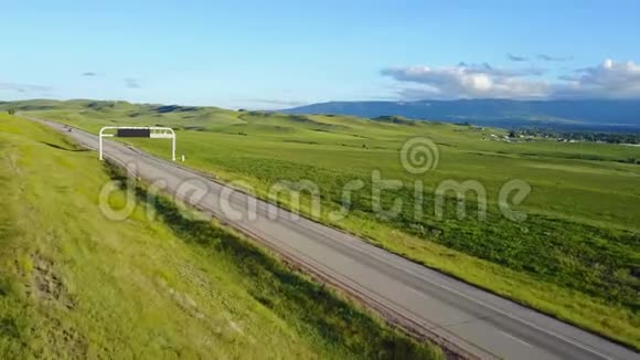 美丽的空中背景拍摄的高速公路穿越宁静的草原丘陵和远山与晴朗的天空视频的预览图