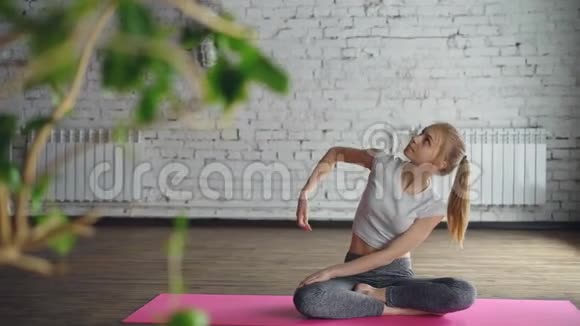 有魅力的女孩正在练习瑜伽弯曲到一边手臂向上然后在轻松的莲花姿势中放松在个人会议上视频的预览图