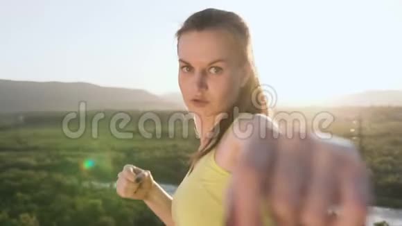 快关门愤怒的踢拳女孩在日落或夏季日出的山顶上表演训练年轻女子视频的预览图
