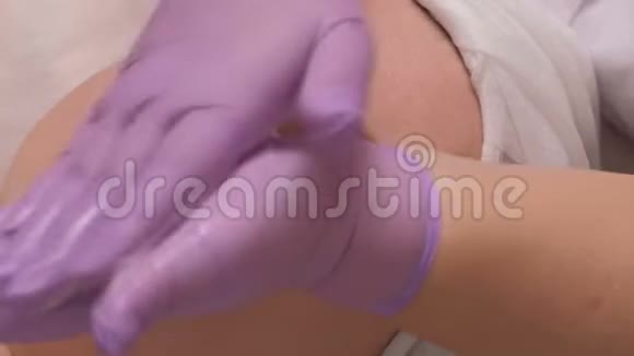 一位戴着紫丁香手套的美容师的手在女性脸上放了一个肥皂溶液手术中的中年妇女视频的预览图