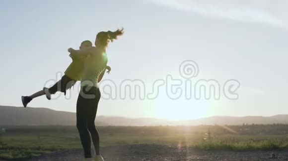 幸福的儿子和母亲一位快乐的运动女性在跑步训练结束后在日落时分和孩子一起在大自然中玩耍视频的预览图