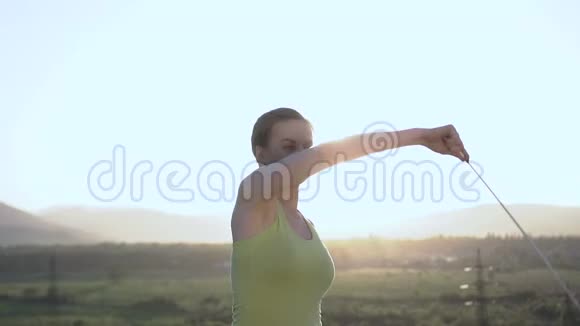 快关门有魅力的女性体操运动员在日出或日落时在户外用蓝色丝带跳舞绿色体操运动员视频的预览图
