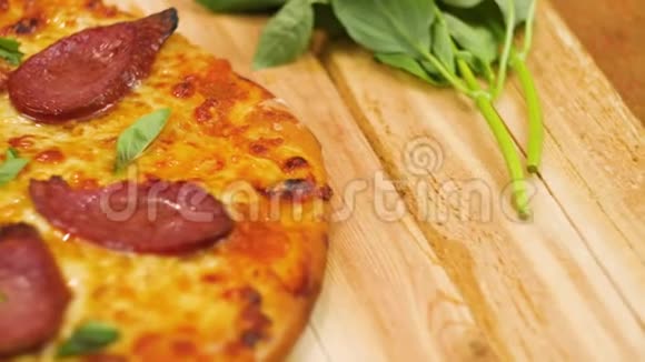 在木桌上摆着美味可口的意大利香肠比萨饼上面装饰着绿色没有男人或女人慢动作靠近顶部视频的预览图