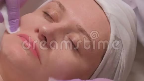 美容中心的中年妇女一位戴着紫丁香手套的美容师的手在上面放了一个肥皂液视频的预览图