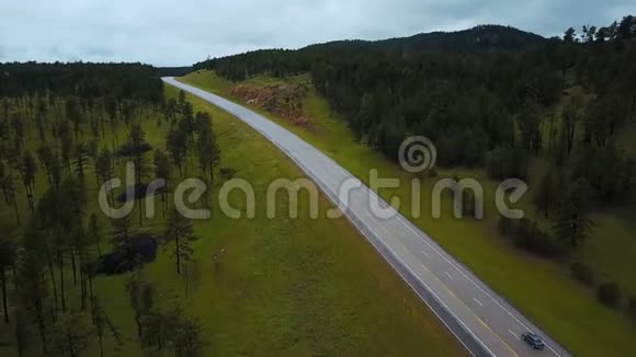 美丽的空中拍摄的银色汽车沿着美国公路行驶在野生绿色森林岩石山与树木视频的预览图