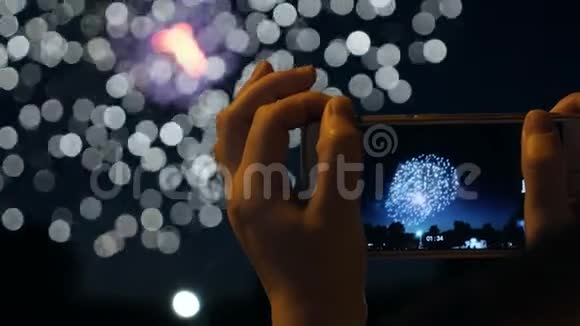 一个女人在智能手机上燃放烟花用博克光背景庆祝烟花视频的预览图