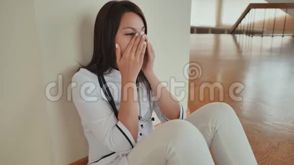 年轻的女医生坐在医院的地板上哭泣视频的预览图
