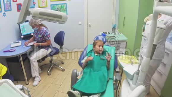 带着一个母亲的孩子在牙医接待处女孩躺在椅子上在她母亲的身后医生和一个视频的预览图