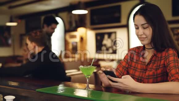 年轻男子认识时漂亮的黑发女人正在酒吧柜台检查智能手机青年视频的预览图