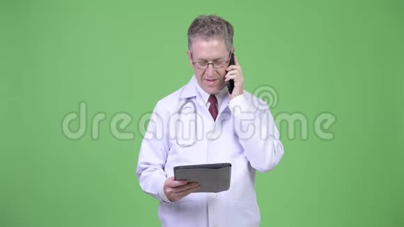 成熟男医生使用数码平板电脑在电话中交谈的肖像视频的预览图
