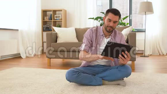 带着平板电脑的男人在家里冥想视频的预览图
