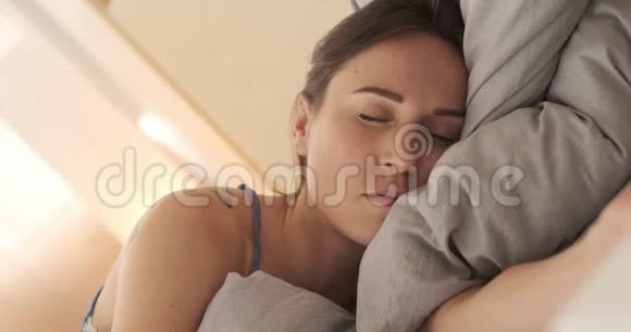 美丽的女人醒来在床上伸展视频的预览图