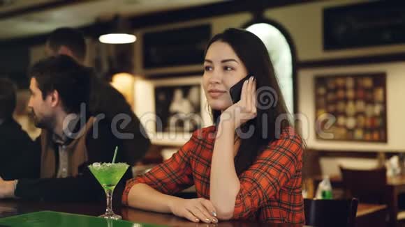 年轻的女人正在用手机说话而坐在酒吧的柜台说话顾客搬进来说话视频的预览图