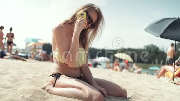 穿比基尼的美女在海滩上打电话视频的预览图