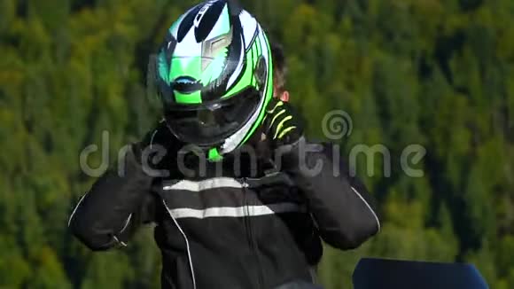 一个骑摩托车的人带着摩托车在山上的年轻帅哥特写镜头他戴着头盔视频的预览图