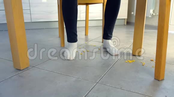 女人在餐桌上吃东西把玉米片摔在地上腿和地板正面视图视频的预览图