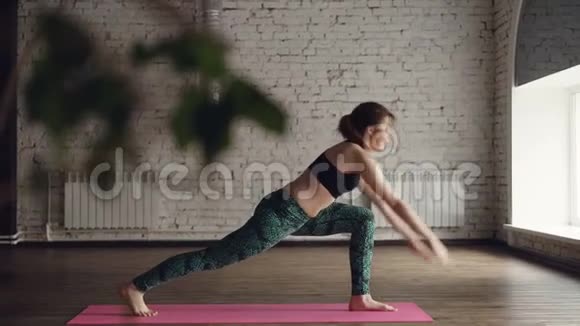 瑜伽老师正在展示一个复杂的体式站在大光工作室的中心在明亮的垫子上女人是视频的预览图