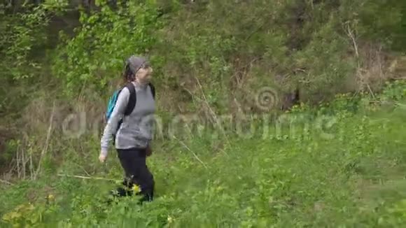 一个背着背包的女人在森林里爬上了一座小山视频的预览图