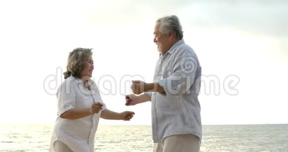 浪漫的亚洲老年夫妇在海滩上跳舞视频的预览图