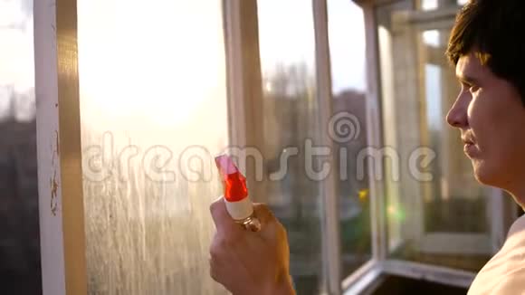 一个带着耳机听音乐在公寓里洗窗户的人窗户清洁器视频的预览图