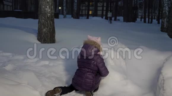 有趣的女孩在寒假晚上散步时玩雪球视频的预览图