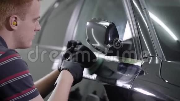 一个洗车工人用特殊工具给一辆黑色汽车上蜡的特写镜头视频的预览图