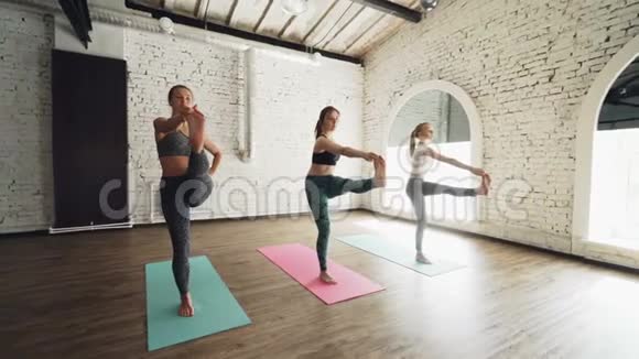 多莉拍摄的漂亮苗条的年轻女性做平衡瑜伽练习在轻阁楼风格的健身房体育器材健身视频的预览图