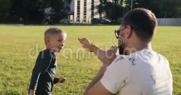 小金发男孩拳击和公园里的男人玩视频的预览图