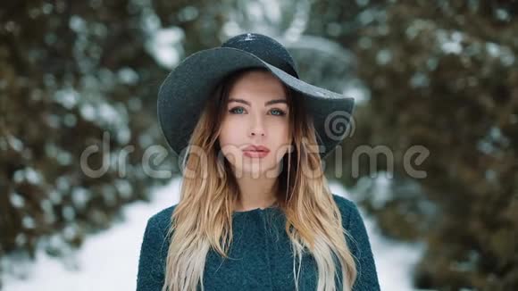 一个金发的年轻漂亮女人的肖像站在森林里的雪地下微笑快乐的女孩看着视频的预览图