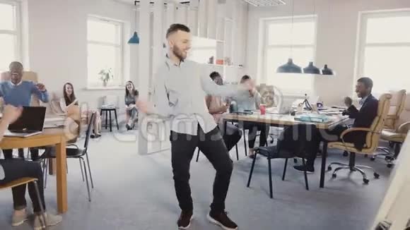 年轻成功的商人在现代光多民族的办公室里跳胜利舞人们鼓掌欢笑4K视频的预览图