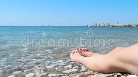 美丽的双腿紧贴着一个不知名的女人坐在海滨女孩把鹅卵石扔进海里一般而言视频的预览图