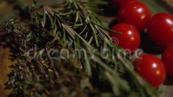 新鲜的迷迭香和美味多汁的红色西红柿躺在厨房的木板特写摄像机从左向右移动视频的预览图