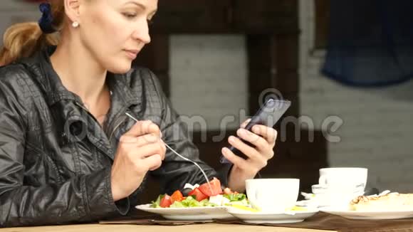 在户外咖啡馆吃沙拉的女商人女孩吃绿色可口的食物和检查你的手机电子邮件4公里视频的预览图
