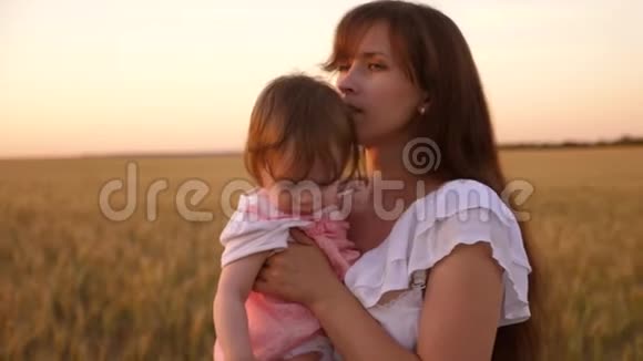 日落时分母亲怀里抱着一个小孩子带着麦子走在田野里慢动作视频的预览图