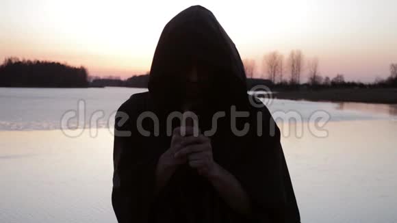 一个和尚拿着十字架在湖岸上祈祷视频的预览图