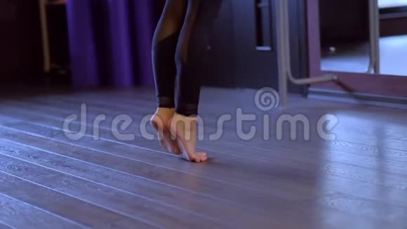 赤足舞者长马尾辫黑色弯曲身体向后脚在芭蕾舞杆上低角度拍摄慢动作视频的预览图