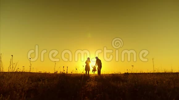 宝宝爸爸妈妈在夕阳下穿过田野和孩子一起玩耍慢动作视频的预览图