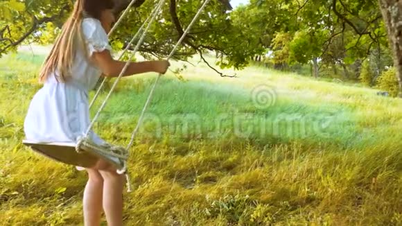 美丽的女人在秋千上摇摆在夏天的公园里笑慢动作视频的预览图