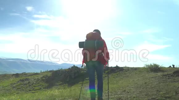 那个带着红色背包的旅行者的女人从山上站起来女人坐着看着雪山看着煤气视频的预览图