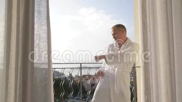 一个穿浴袍的男人在露台上跳舞动作缓慢4K视频的预览图