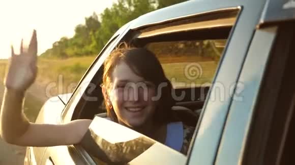 美丽的长发女孩骑着一辆车双手放在窗前微笑着挥动着她的手怒视着视频的预览图
