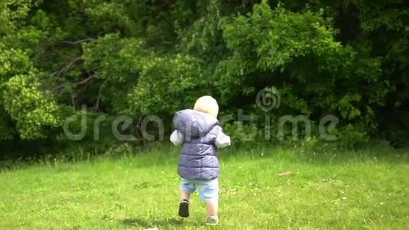 小男孩在城市公园的草地上迈出第一步视频的预览图