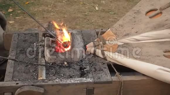 铁匠在锻造厂工作老式风箱铁匠用泥炉把钢坯放在热煤上视频的预览图