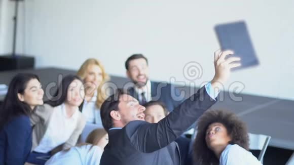 在演示会议期间混合的商务人士在平板电脑上拍摄自我照片视频的预览图